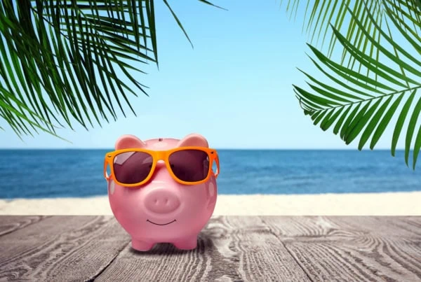 a piggy bank wears sunglasses while standing on a boardwalk.