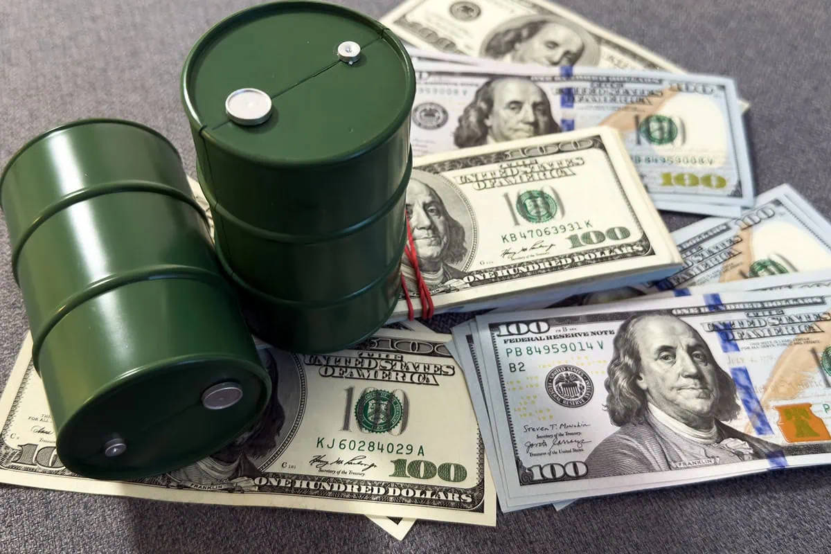 March's Headline Inflation Spikes to Highest Point Since 2022 2 barrels of oil sitting atop stacks of cash.