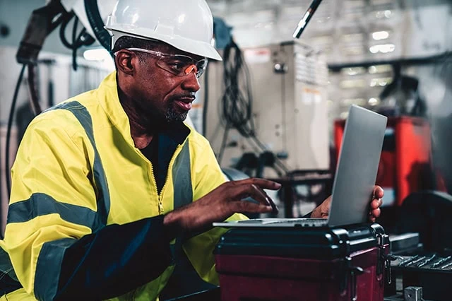Young and the Invested's Best Tech Stocks to Buy Now 4 Engineer working with laptop computer in a factory.