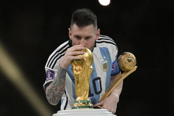 Argentine forward Lionel Messi kisses a World Cup trophy in 2022 in Qatar.