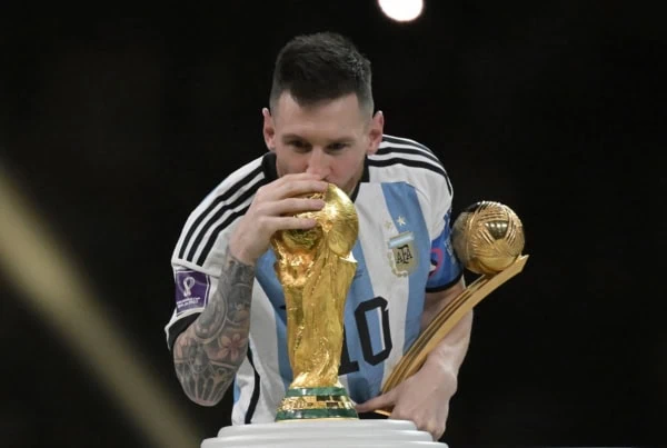 Argentine forward Lionel Messi kisses a World Cup trophy in 2022 in Qatar.
