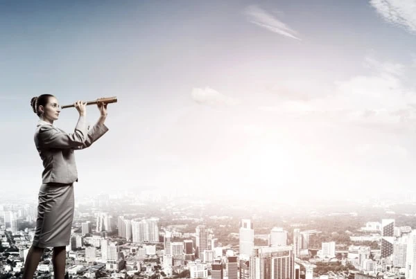 a businesswoman looks out with a spyglass.