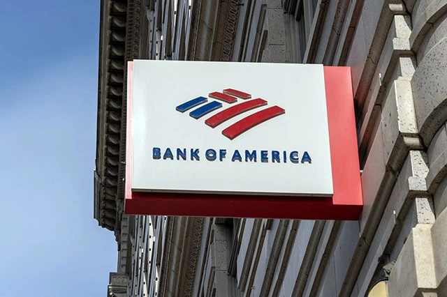 a small bank of america sign juts out of a city building.
