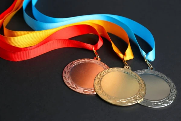 a gold medal silver medal and bronze medal overlap each other while sitting on a table.