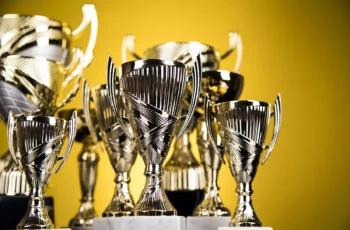 trophies of various sizes and shapes are up against a yellow background.