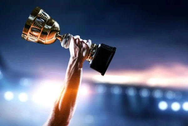 an athlete raising a trophy into the sky against the background of a stadium.