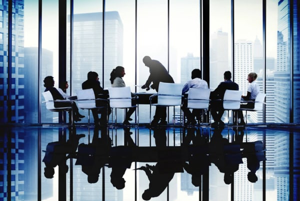 a group of business executives sit around a table during a meeting.