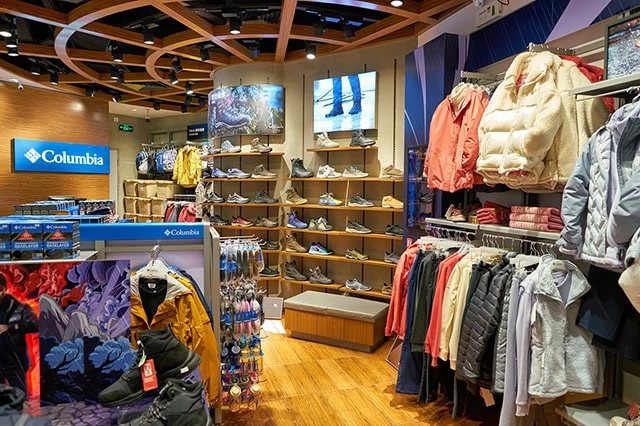 the inside of a columbia sportswear store with many jackets and shoes on shelves and racks.