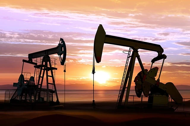 the silhouettes of oil rings against a sunset.
