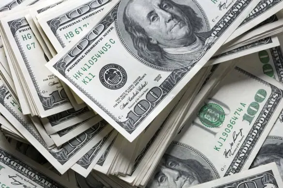 hundred dollar bills stacked and swirled across a table.