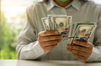 a person counts many hundred dollar bills.