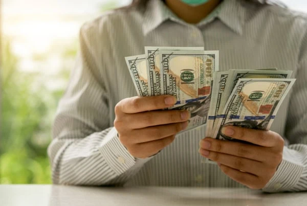 a person counts many hundred dollar bills.