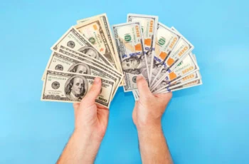 a pair of hands fan out a bunch of old and new hundred dollar bills.