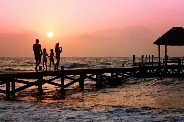 family walking along pier sunset