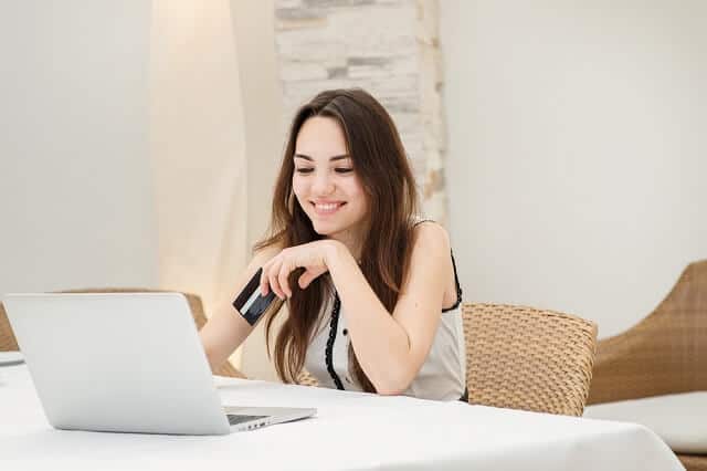 girl sitting at laptop smiling with card in hand