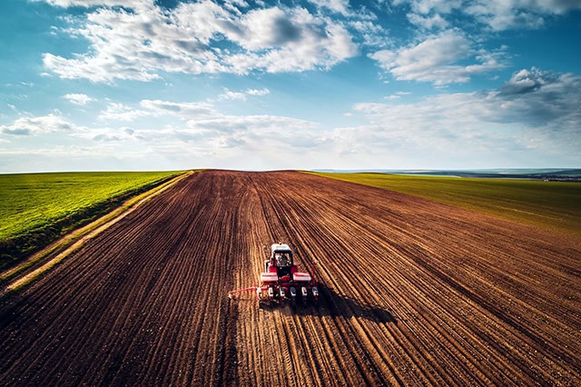 a red tractor going over farmland.