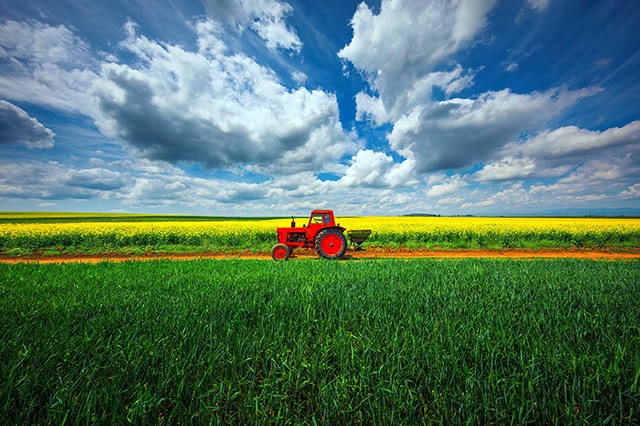 a red tractor going over farmland.