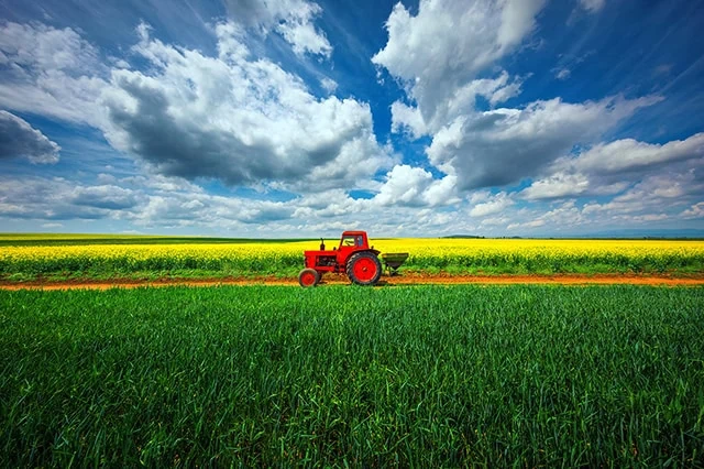 33 Best Passive Income Ideas + Passive Income Investments 25 a red tractor going over farmland.