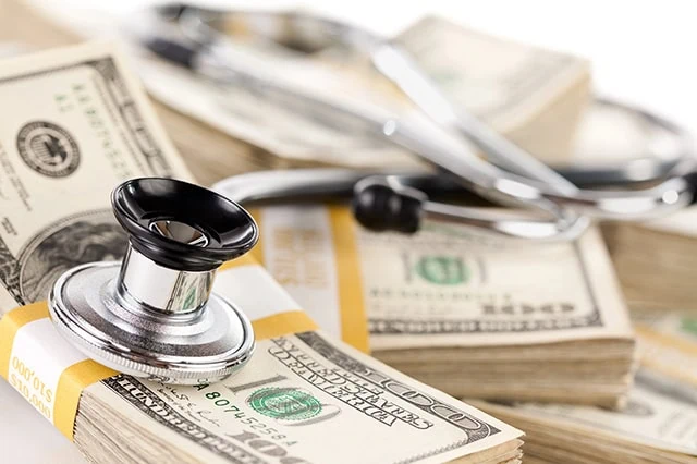 a stethoscope sits on a wad of dollars.