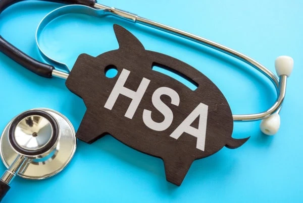 a stethoscope wrapped around a flat wooden piggy bank carving that says H S A.