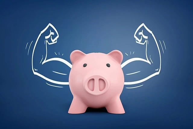 Best Vanguard Funds to Hold in an HSA 2 a piggy bank standing in front of a drawing that makes the piggy bank look like it has muscles.