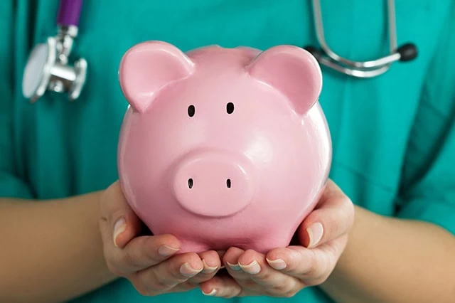 HSA Contribution Limits for 2026 + 2027 4 a nurse in green scrubs holds a pink piggy bank.