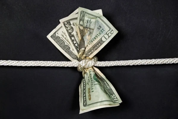 a rope tightens around 20 50 and 100 dollar bills.