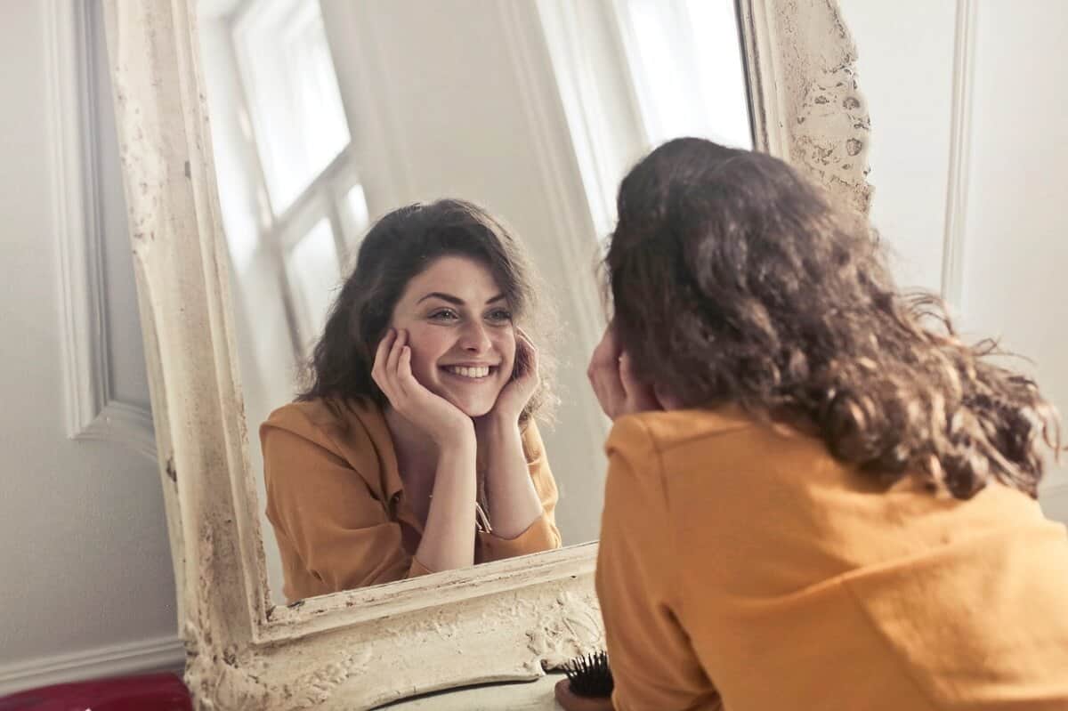 invest in yourself smiling woman in mirror