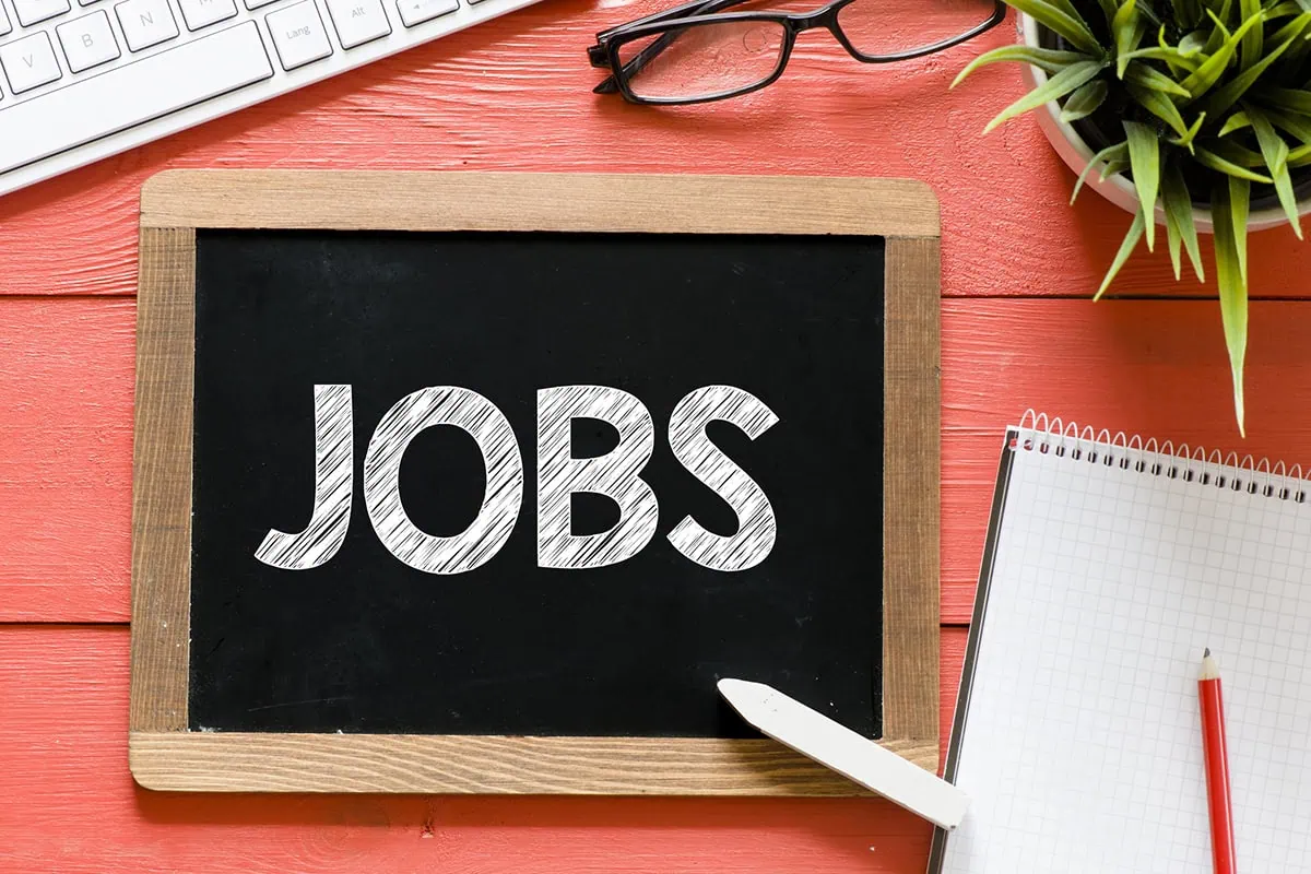 the word jobs is written on a personal chalkboard sitting on a desk.