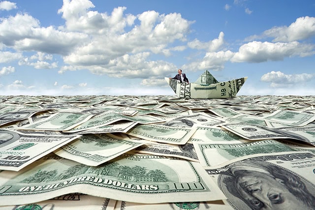 a businessman sails on a sea of cash in a boat made out of cash.