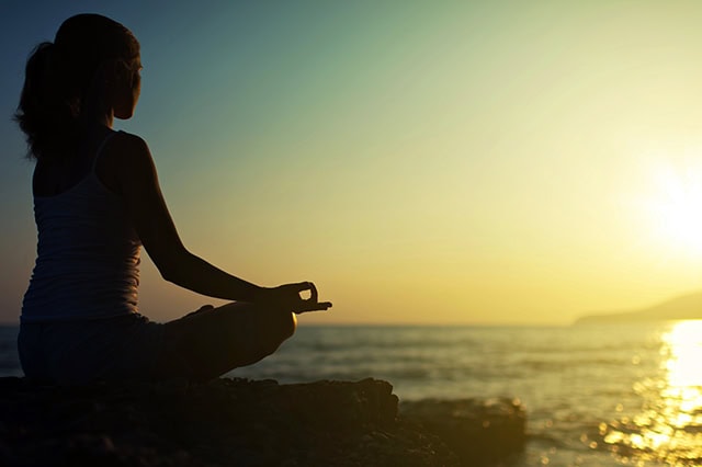 a woman performing yoga at sunrise.