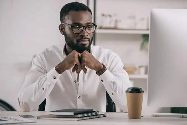 man looking at computer with investments medium