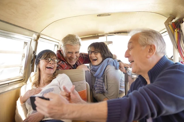 Group of senior friends in camper van using smartphone