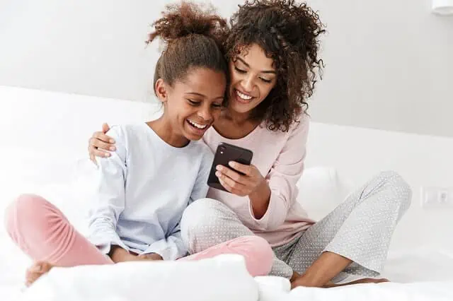 mother and daughter on bed looking at phone