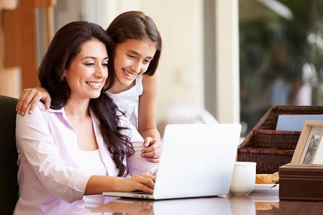 mother and daughter using laptop smiling