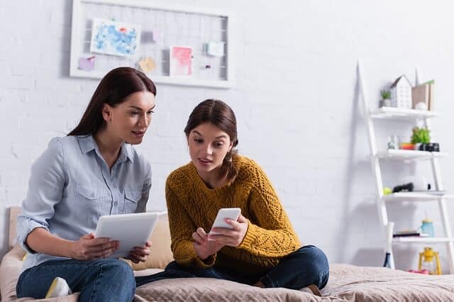 mother and daughter comparing smartphone and tablet