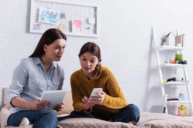 mother daughter comparing smartphone and tablet medium