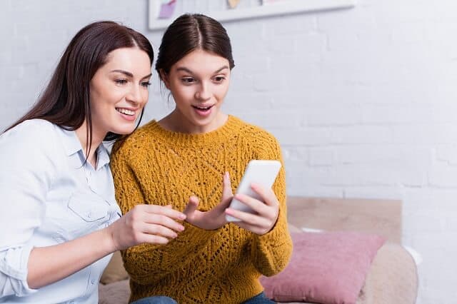 mother daughter using smartphone medium