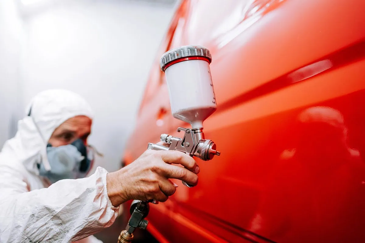 15 Dividend Kings for Royally Resilient Income 5 a man using an industrial spray painter on a car door.