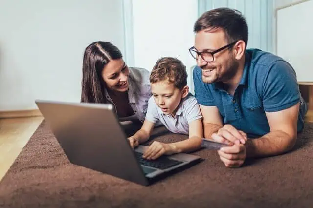 parents with child using a computer and card