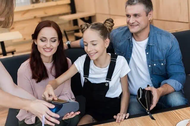 parents with daughter paying with card