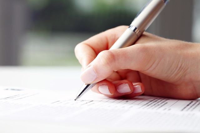 Businesswoman's hand with pen completing personal information on a form