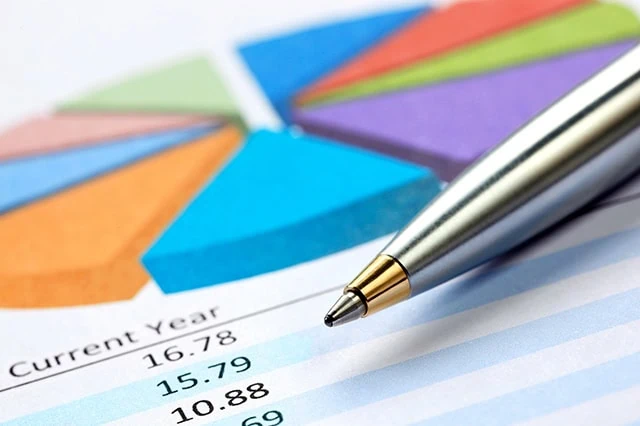 a pen resting on a mutual fund report with a pie chart and several return figures.