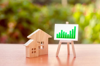 wooden houses and a chart showing growth on an easel.