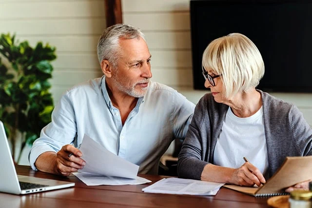 Our Guide to the New Senior Tax Deduction 10 a middle-aged couple fills out documents at their table.