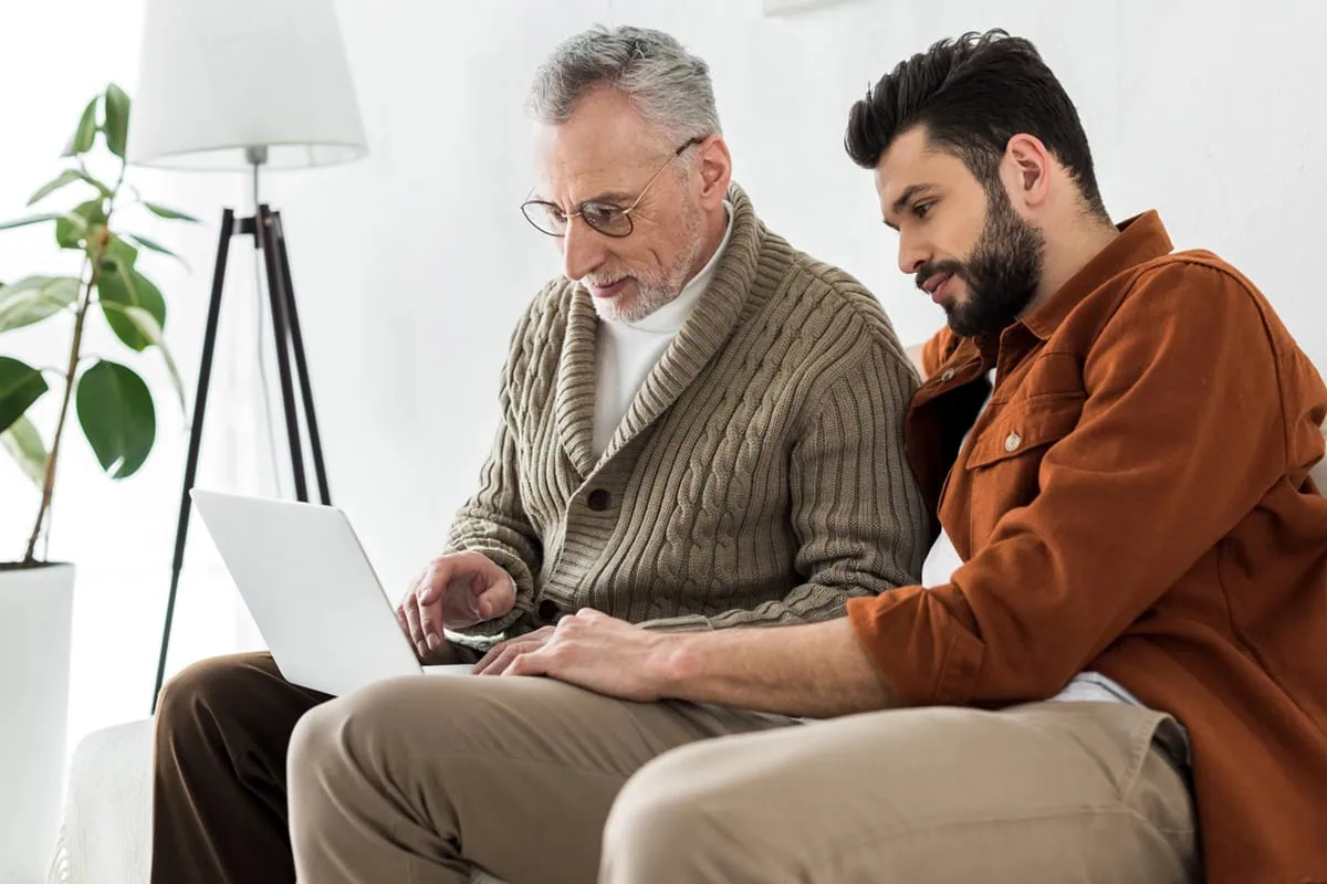 Financial Caregiving: How to Manage a Loved One's Finances 14 an adult male and his father look at a laptop.
