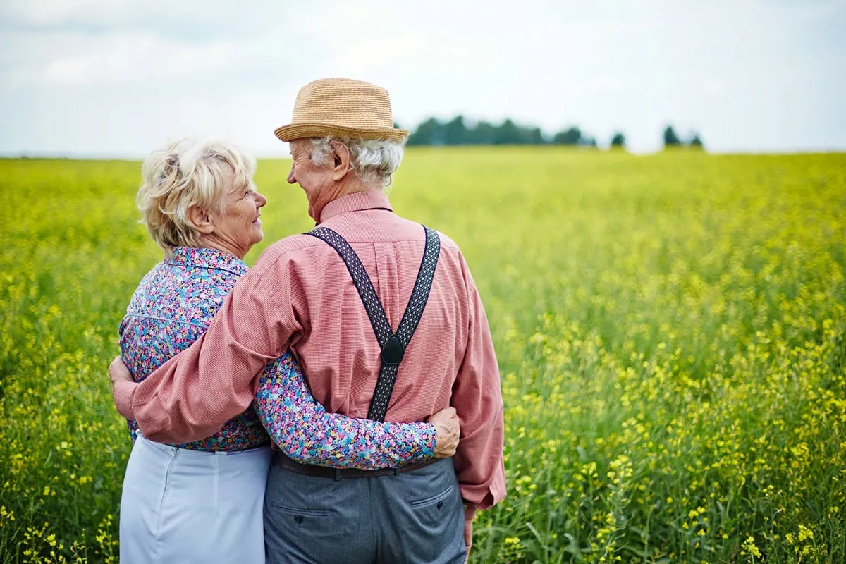 Avoid Retirement Anxiety: 10 Tips That Will Help You Retire With Confidence 5 an affectionate senior couple enjoys a summer day while looking at a vast field.