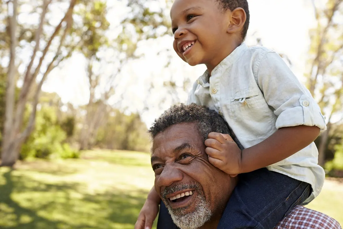Avoid Retirement Anxiety: 10 Tips That Will Help You Retire With Confidence 3 a grandfather holds his grandson on his shoulders.