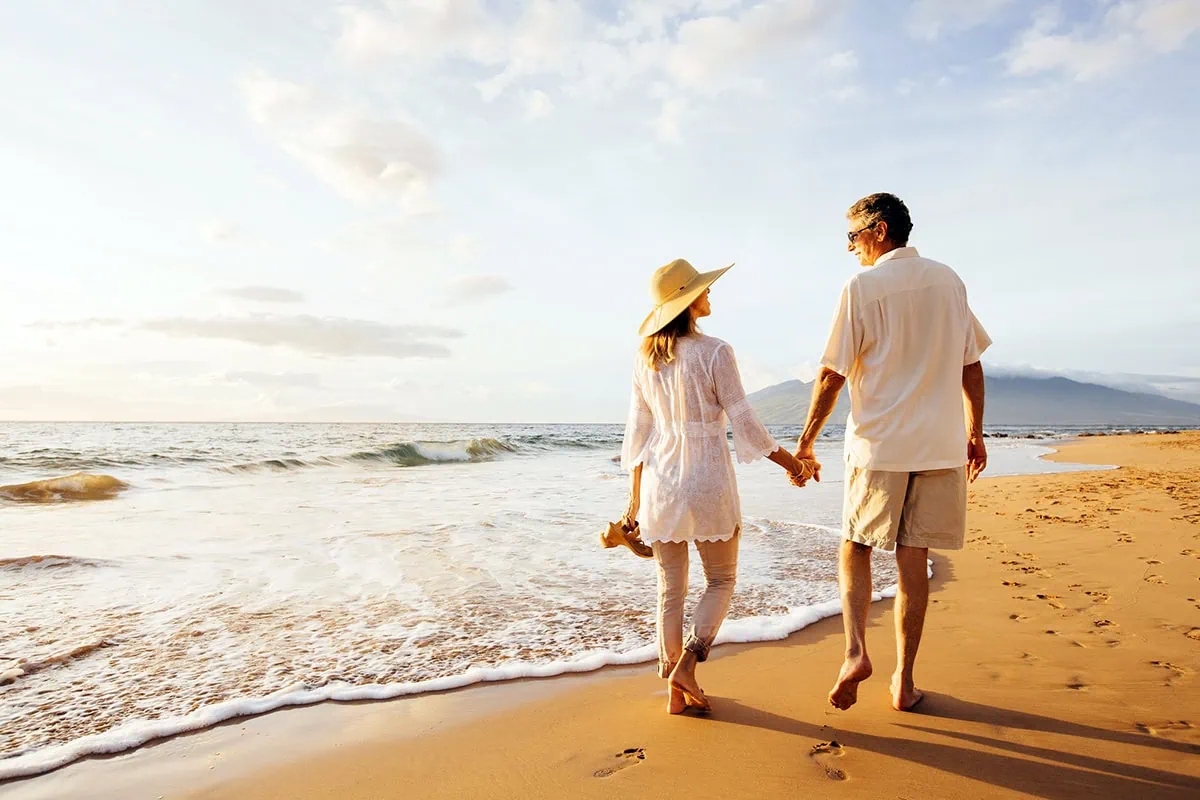 iShares Target-Date ETFs: A Retirement Tool for All 4 a retired couple walks barefoot on a beach on a sunny day.