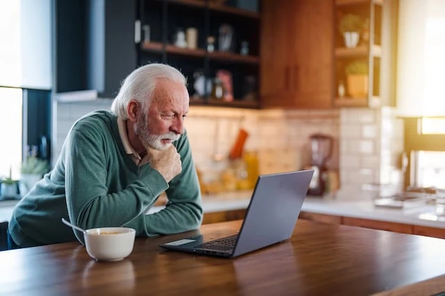 Our Guide to the New Senior Tax Deduction 7 senior man breakfast kitchen cereal laptop 640